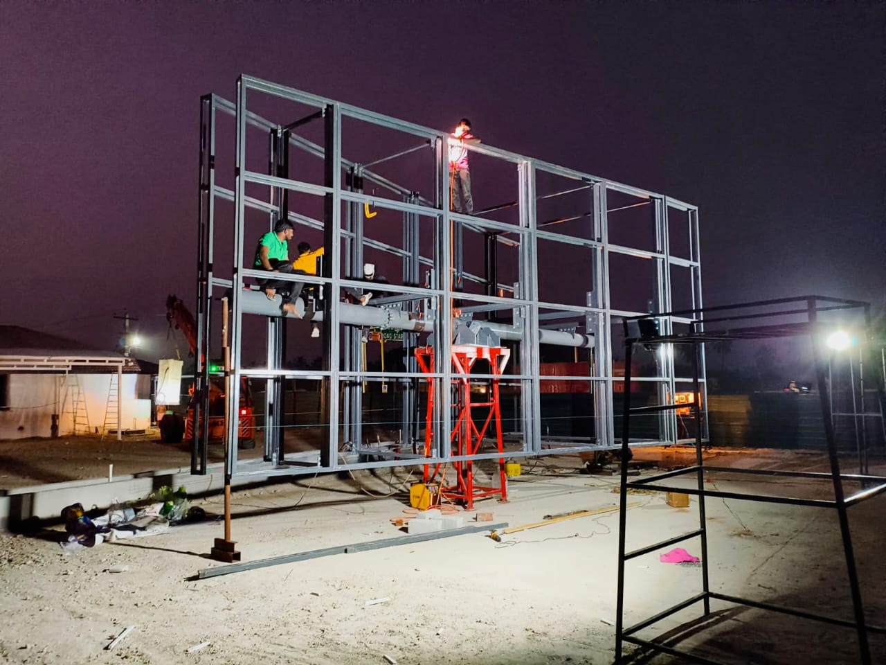 Welder on a pole chord, sparks flying during night fabrication